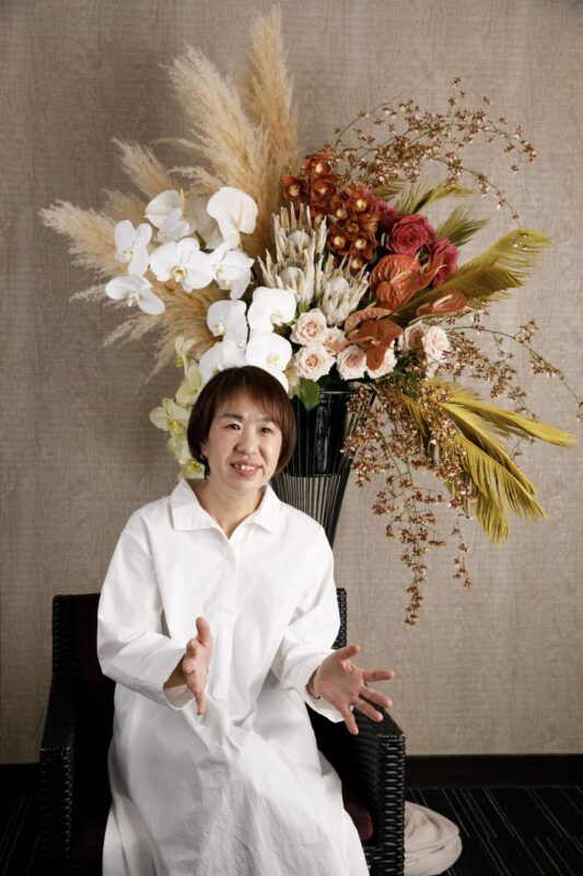 オシャレなスタンド花の前でロクロを回すチヨ